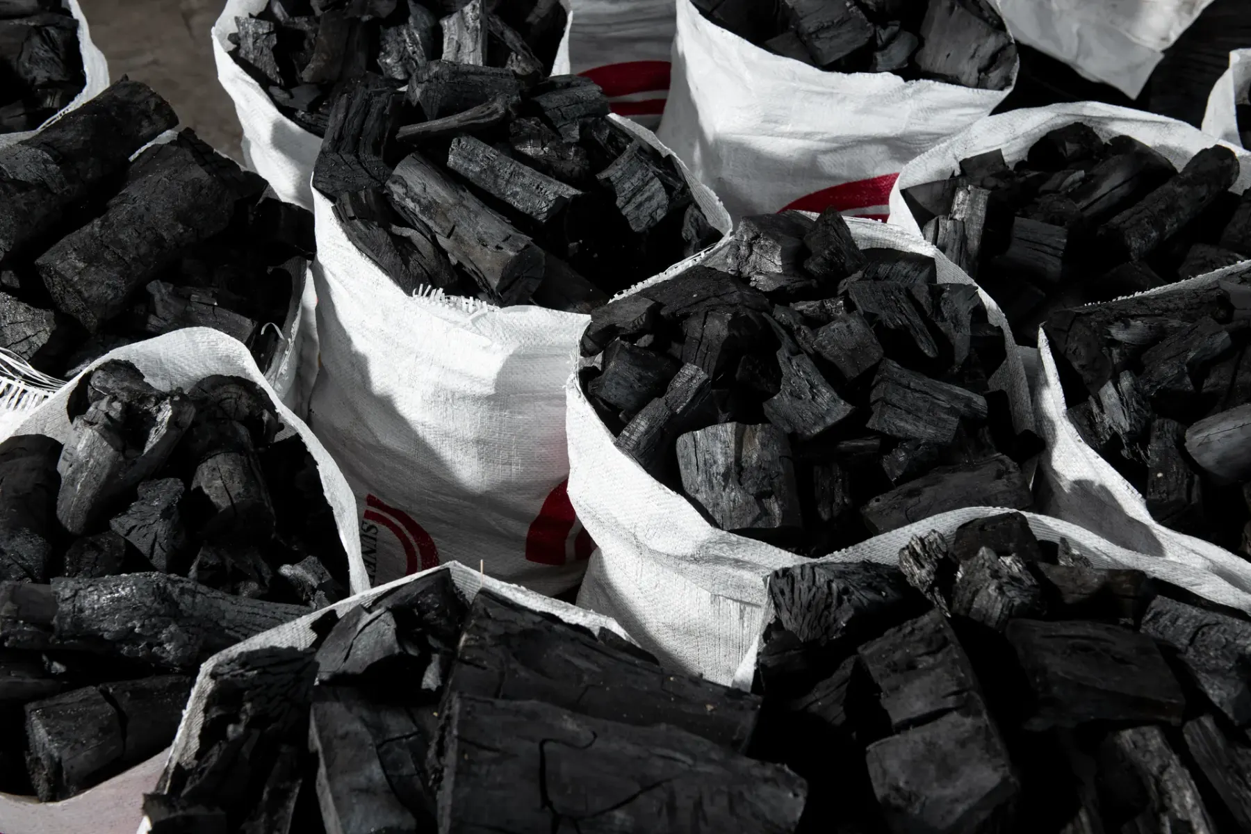 Hardwood lump charcoal in open woven sacks