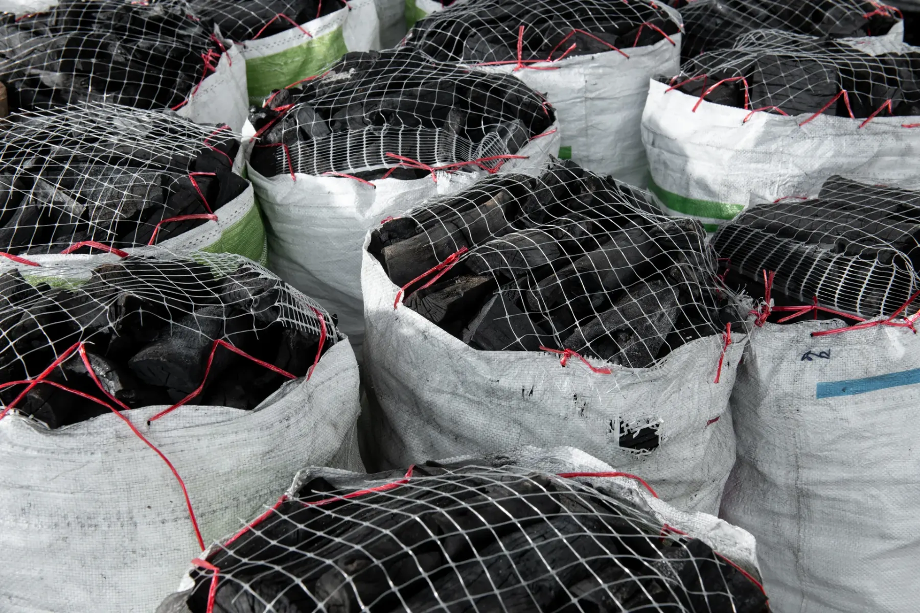 Bulk charcoal in netted woven sacks