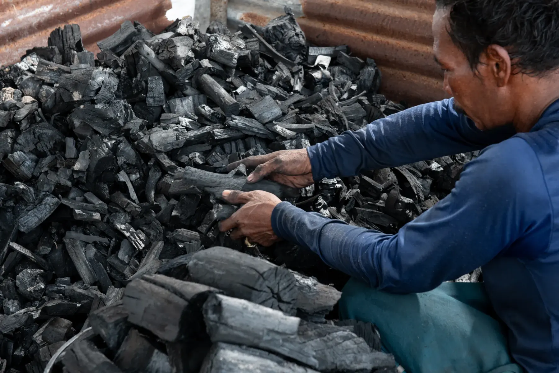 Worker grading charcoal by hand for quality control