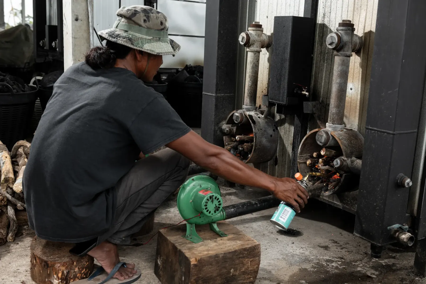 Kiln operator lighting a carbonization kiln at the Carbon Bridge factory